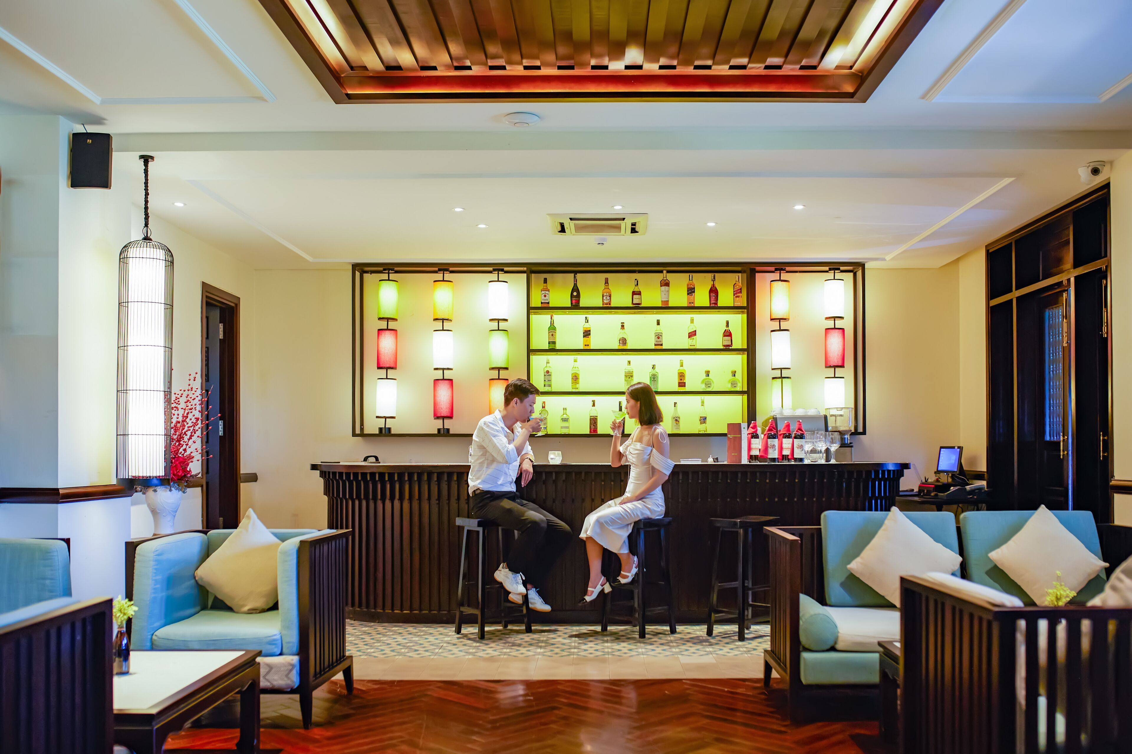 A bar area with stools, a bar counter, and a variety of bottles.