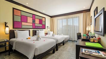 A hotel room with two beds, a desk, a chair, a lamp, a large abstract painting, and a window with curtains.