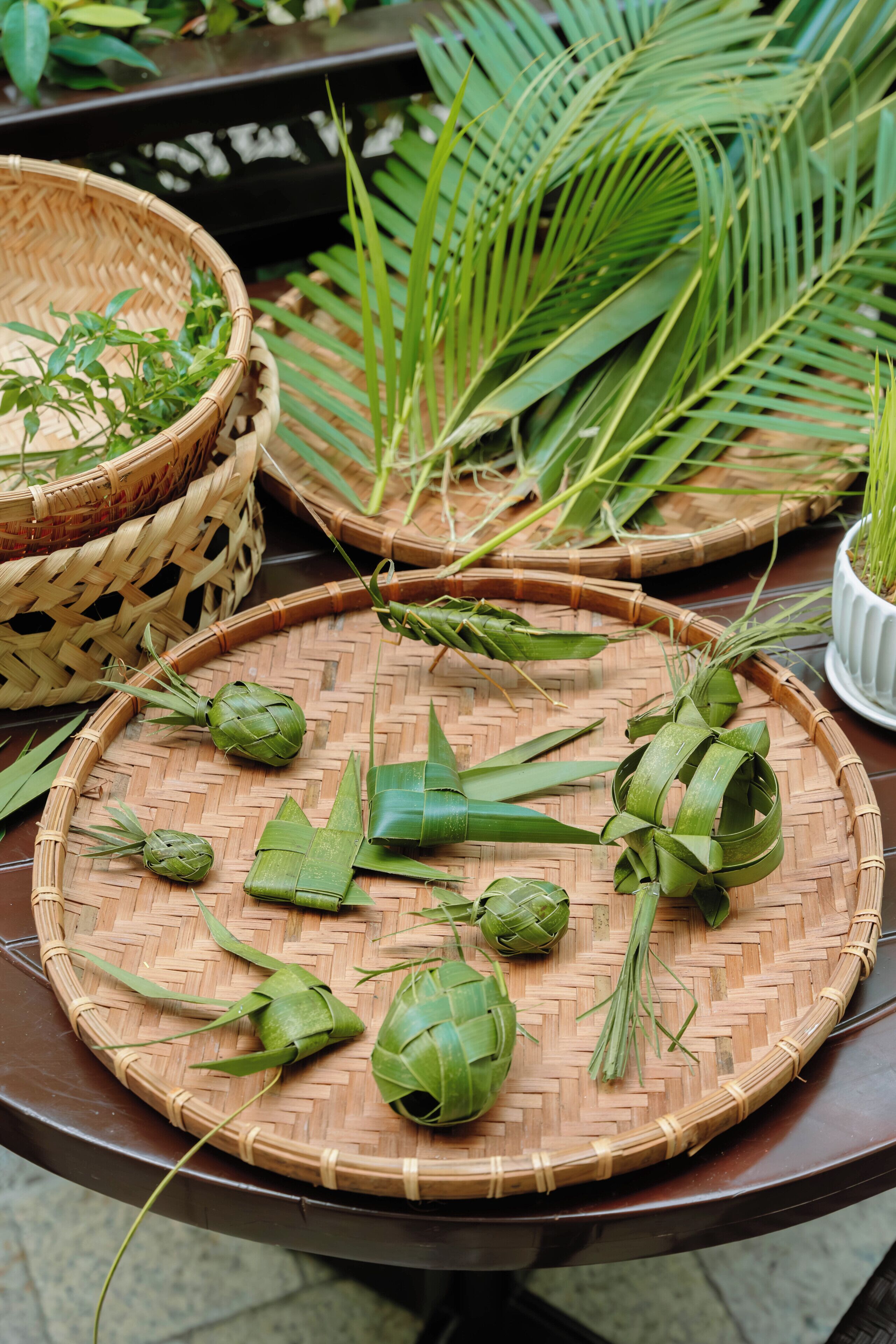 Una cesta trenzada con hojas verdes y un tapete tejido sobre una mesa.
