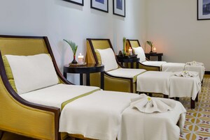 Egy sorban négy, wellnessközpontokban használatos ágy áll, mindegyik fehér ágyneművel van bevonva, és fából készült fejrészük van. Mindegyik ágy mellett egy kis asztal található, rajta egy gyertyával és egy növény egy kis edényben.