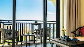 A balcony with wicker furniture, a table, and a bowl of fruit.