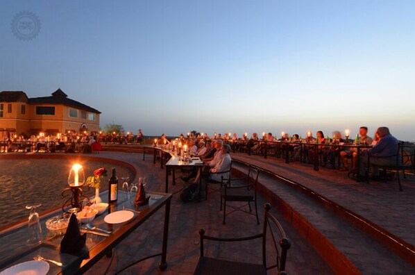 An outdoor dining area with tables set for a meal, overlooking a body of water.