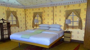 A room with a bed, two nightstands, a lamp, and curtains. - Raisar Camp (Bikaner)