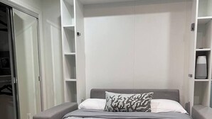 Ein Schlafzimmer mit Bett, Kleiderschrank und einer eingebauten Regallösung.
