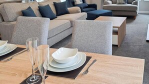 Un soggiorno moderno con zona pranzo, che include un divano, un tavolino e un tavolo da pranzo apparecchiato con piatti e bicchieri.