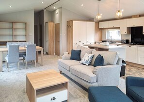 A modern living room with a sofa, a coffee table, and a dining area with chairs and a table.