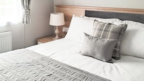 Un letto rifatto con coperta trapuntata, una lampada da comodino e due cuscini.