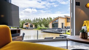 En modern inredning med ett stort fönster som vetter mot en vattenyta och två trähus.