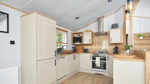 A compact kitchen with white cabinets, a stove, and a microwave.