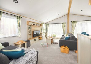 Ein modernes Wohnzimmer mit Fernseher, Sofa und Couchtisch.