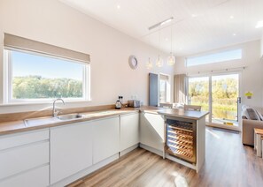 Eine moderne Küche mit einem großen Fenster, einem eingebauten Weinkühler und Blick ins Freie.