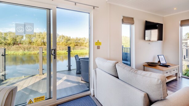 A modern interior with a sofa, a TV, and a view of a lake.