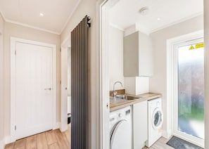 Une cuisine compacte équipée d’un lave-linge, d’un évier et d’une porte dotée d’un panneau coulissant.