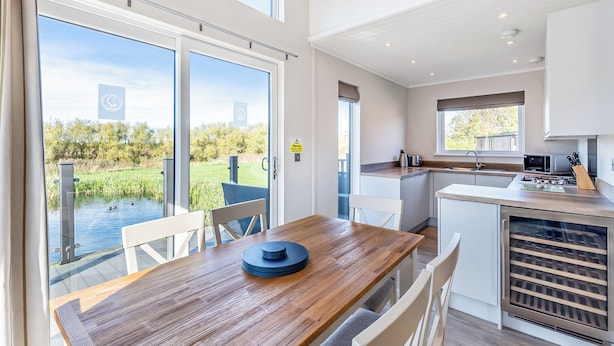 A modern kitchen with a view of a pond, wooden dining table, and white cabinets. - 3 bedroom accommodation in Poulton-Le-Fylde (Poulton-Le-Fylde)