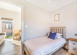 A bedroom with a bed, bedside table, and a view of the outside. - 3 bedroom accommodation in Poulton-Le-Fylde (Poulton-Le-Fylde)
