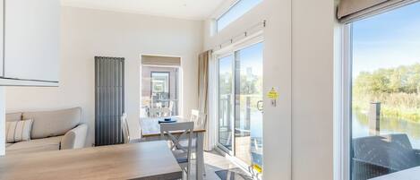 A modern room with a sofa, a dining table, and a view of a body of water.