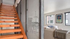 Eine Treppe mit Holzdielen und Metallgeländern, die zu einem Raum mit einer Couch und einem Fenster führt.