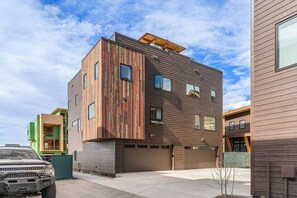 A modern multi-story building with a garage and a car parked in front. - Rooftop Retreat! Pet friendly, Gorgeous Rooftop Sanctuary with Hot Tub and Firepit (Steamboat Springs)