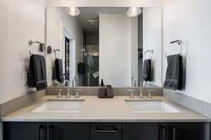 A modern bathroom with two sinks, a large mirror, and black towels. - Rooftop Retreat! Pet friendly, Gorgeous Rooftop Sanctuary with Hot Tub and Firepit (Steamboat Springs)