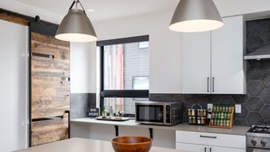Eine moderne Küche mit einer Wand in Holzoptik, einer großen Kochinsel, einer Mikrowelle, einem Gewürzregal und einem Herd.
