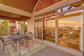 A covered patio with a table and chairs, large sliding glass doors, and a view of the interior.