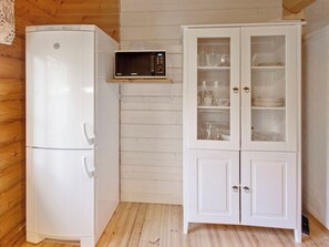 A compact kitchen with a white refrigerator, a microwave, and a cabinet with glass doors.