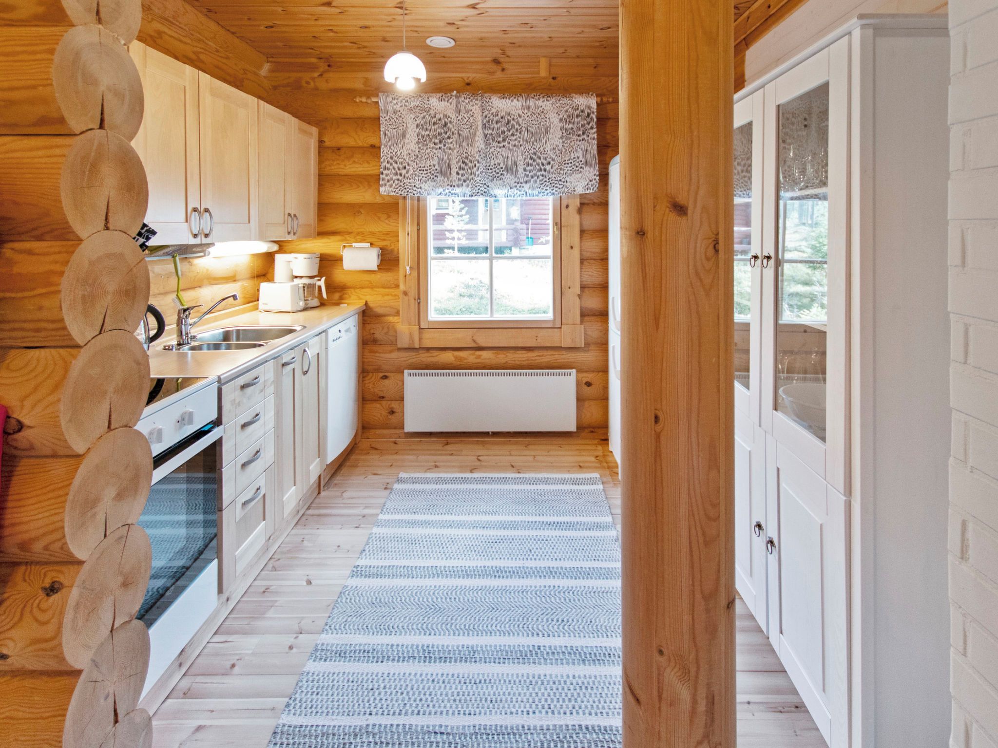 L’intérieur d’un chalet en bois comprend une cuisine, une fenêtre donnant sur un paysage agréable et un radiateur.