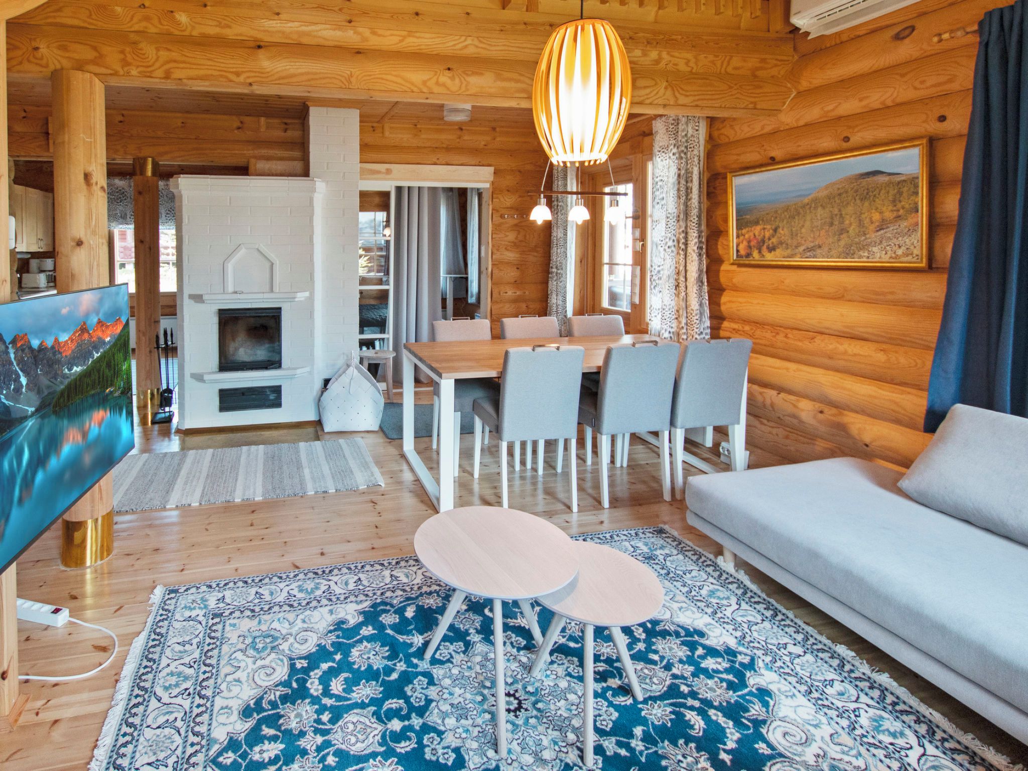 A cozy cabin interior with a dining area, sofa, and fireplace.