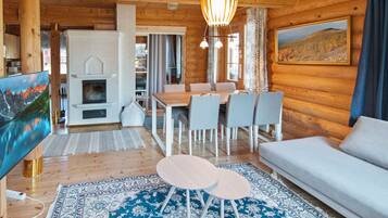 A cozy cabin interior with a dining area, sofa, and fireplace.