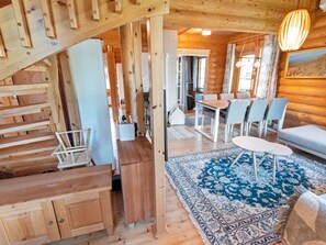 Ein Holzinnenraum mit Treppe, Essbereich und Sitzgelegenheiten.