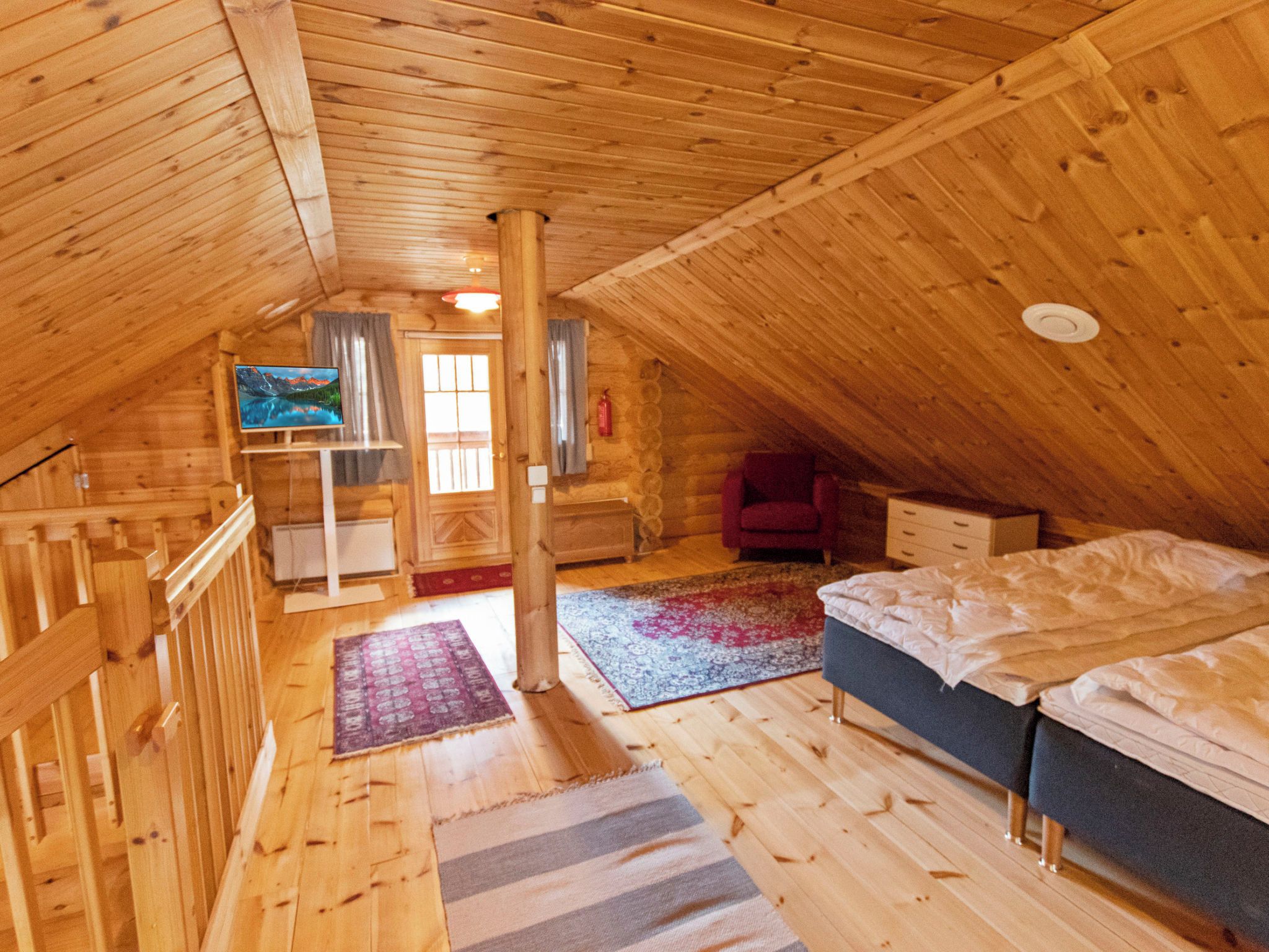 A cozy attic bedroom with wooden walls and a sloped ceiling.