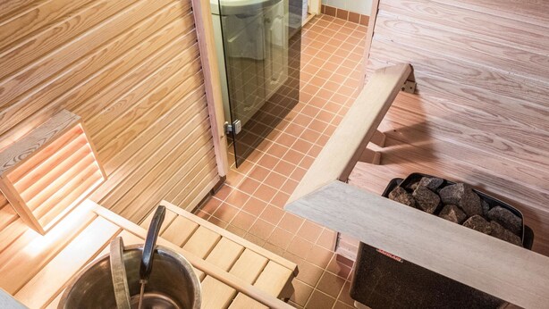 A wooden interior with a metal sink, a bench, and a trash bin. - Kivakatti by Interhome (Sotkamo)
