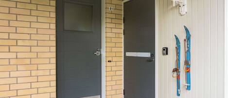 A door with a metal step and a doormat, a mailbox, and skis leaning against a wall.