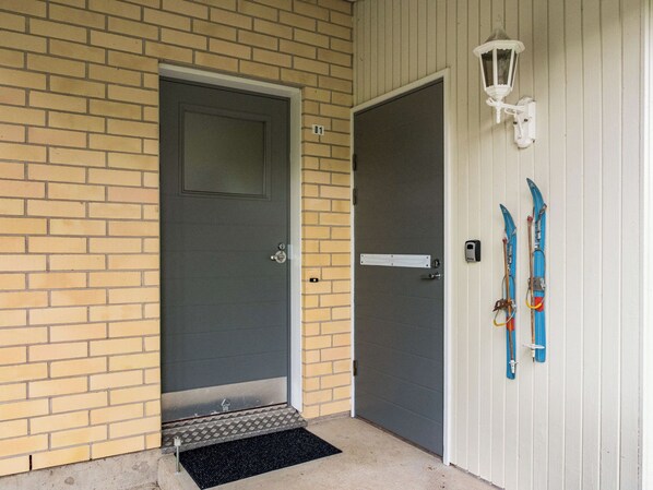 A door with a metal step and a doormat, a mailbox, and skis leaning against a wall.