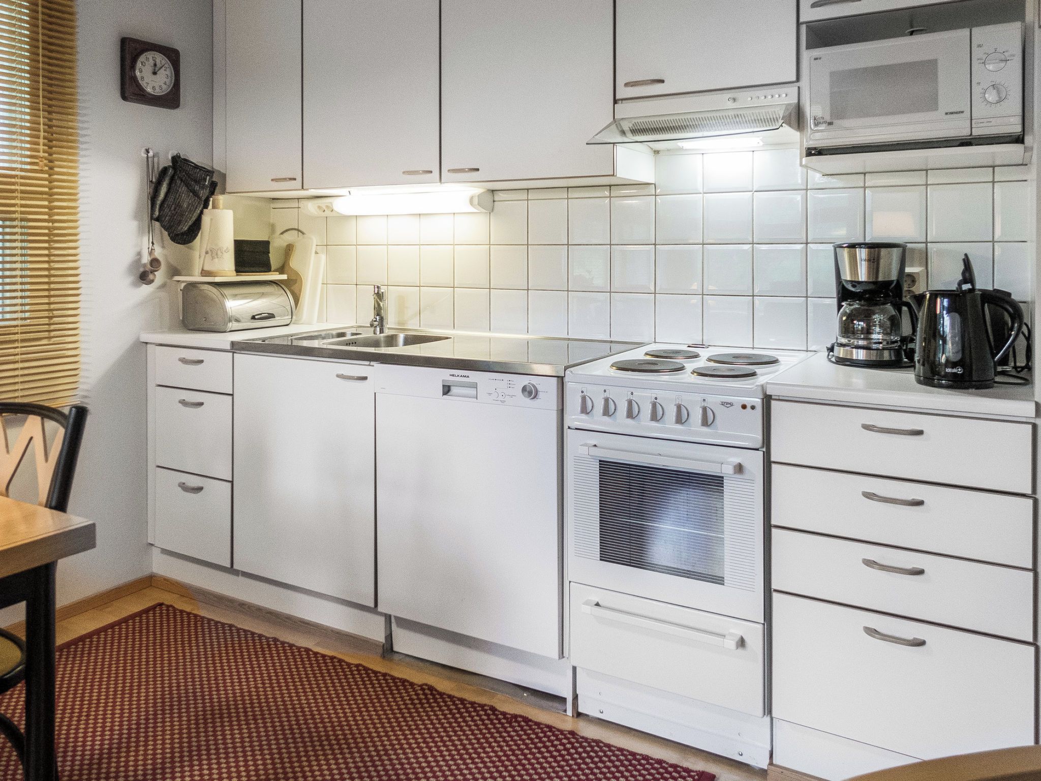 Une cuisine avec des armoires blanches, une cuisinière, un four à micro-ondes et une machine à café.