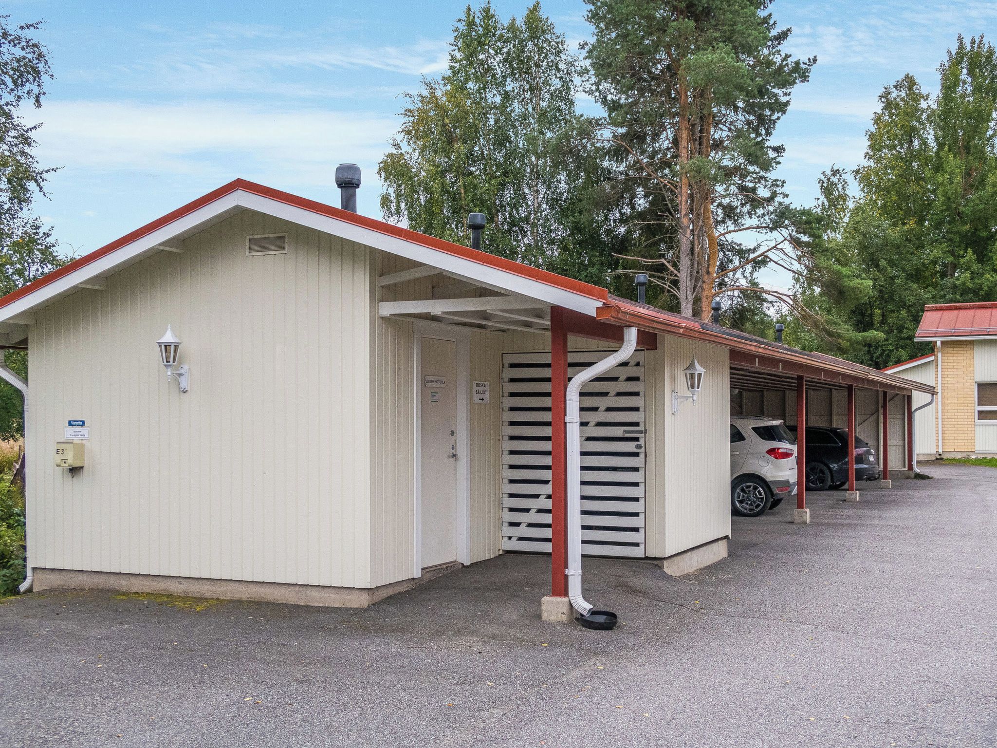 A single-story building with a red roof and a covered parking area.