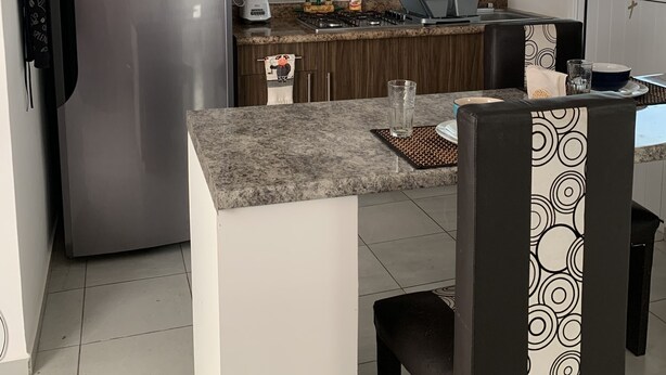 Eine kompakte Küche mit Edelstahl-Kühlschrank, Gasherd und Holzausstattung.