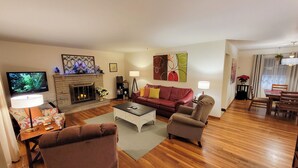 Ein Wohnzimmer mit Kamin, Fernseher, einer Couch und einem Essbereich.