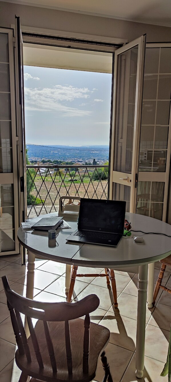 A balcony with a table, a laptop, and a chair.