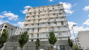 A modern multi-story building with a unique facade featuring vertical slats. - Chic apart with parking near Paris (Nanterre)