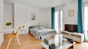 A modern bedroom with a bed, a glass coffee table, a TV, and a desk with chairs. - Chic apart with parking near Paris (Nanterre)