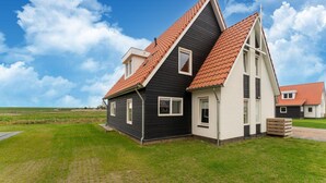 Une maison moderne à deux étages, dotée d’un toit en pente, d’un petit garage attenant et d’une pelouse bien entretenue.