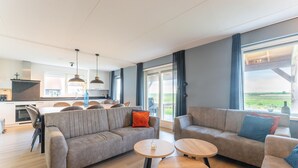 Un salon moderne avec un canapé, deux tables rondes et un coin repas avec des chaises.