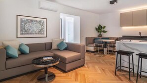 A modern living room with a sofa, coffee table, and a dining area with a bar. - Belvilla by OYO Palm Loggia (Meran)