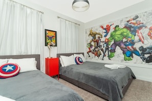 A bedroom with two beds, a large superhero-themed mural, a framed comic book, and a red nightstand.