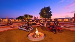 Une cour avec un foyer, des tentes et des personnes vêtues de costumes traditionnels.