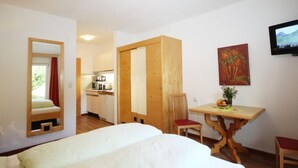 Una camera d'albergo con un letto, un tavolino con sedie, una televisione e un quadro appeso al muro.