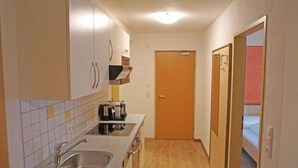 Cocina compacta con fregadero, estufa y armarios.