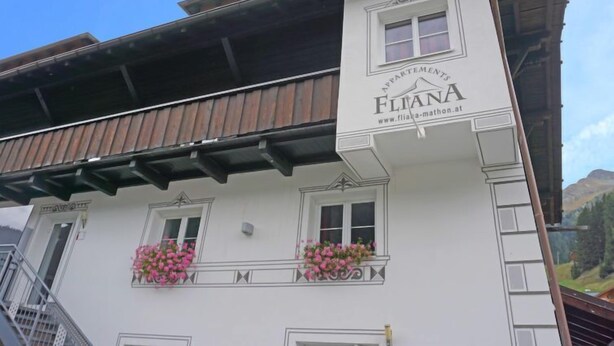 Un edificio con un letrero que dice "FLIANA APARTMENTS" y una dirección web.