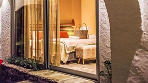 A modern bedroom with a large sliding glass door, a bed with a white comforter, a wooden headboard, and a hanging light fixture. - Garden Suite by Interhome (Ronco sopra Ascona)